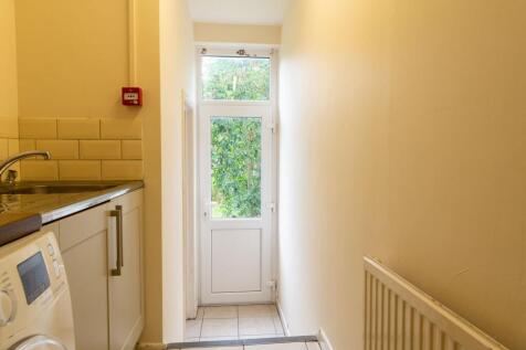 Bright narrow hallway with a rear door and wind...