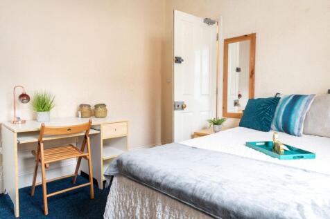 Bright, neatly styled bedroom with a comfortabl...