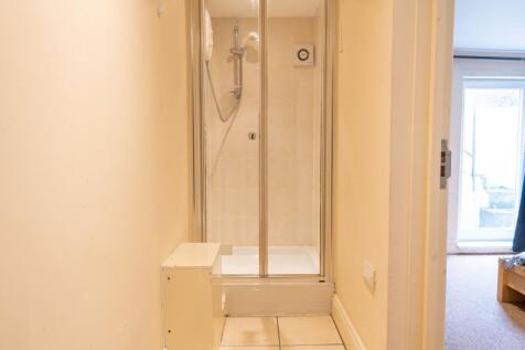Compact tiled shower cubicle set within a narro...