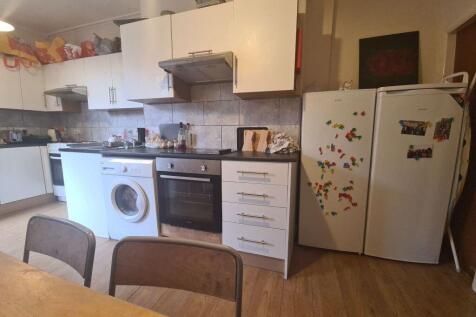 A modern kitchen with white cabinetry and woode...