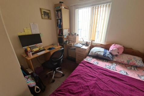 A compact bedroom featuring a single bed with c...