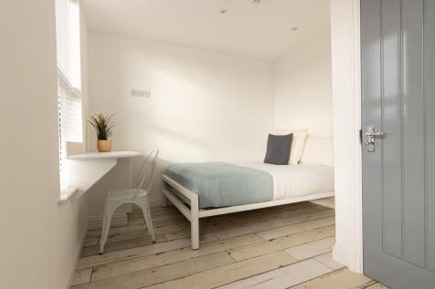 Bright, minimalist bedroom with pale wood floor...