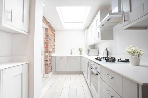 Bright, modern galley kitchen with white cabine...