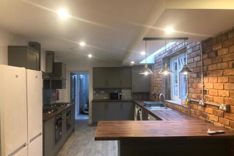 Modern fitted kitchen with a long wooden breakf...