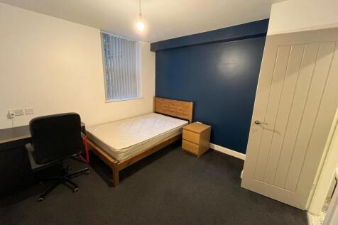 Neat single bedroom with a wooden bed frame, ma...