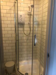 Bright tiled shower enclosure with modern curve...