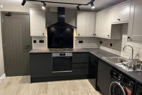 Contemporary fitted kitchen with matte black lo...
