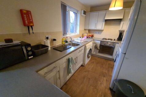 Bright galley-style kitchen with white cabinetr...