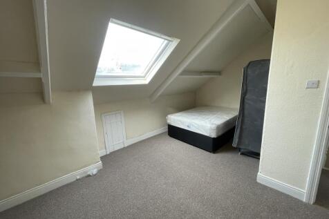 Bright attic bedroom with a sloped ceiling and ...