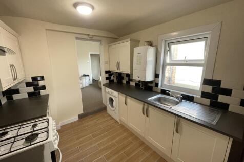 Modern galley kitchen with cream cabinetry, bla...
