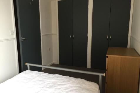 A tidy bedroom featuring a metal bed frame with...