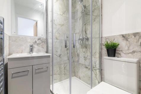 Bright modern bathroom with a glass-enclosed sh...