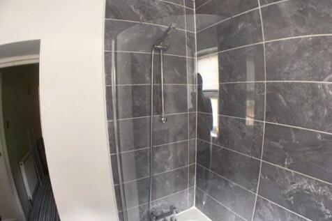 Stylish tiled bathroom with a shower over the b...