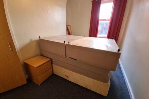 Compact furnished bedroom with a large bed, fit...