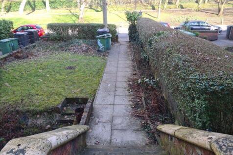Paved front pathway flanked by well-kept hedges...