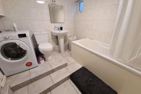 Bright, tiled bathroom with a bathtub and separ...