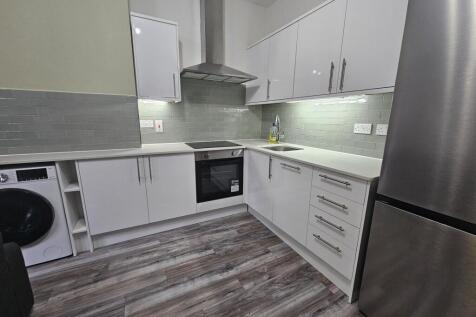 Modern fitted kitchen with white cabinetry, int...