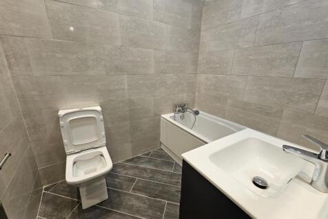 Modern tiled bathroom with a bathtub, wall-moun...