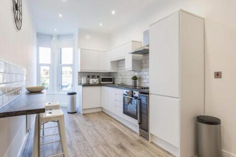 Bright modern kitchen with white cabinetry, int...