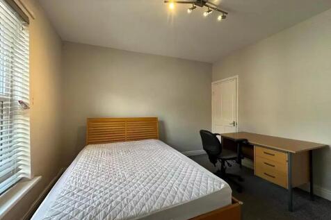 A tidy double bedroom featuring a wooden bed fr...