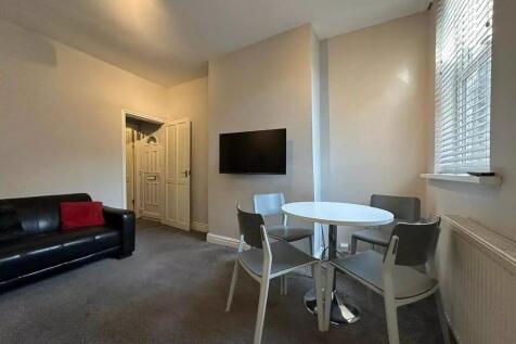 A cozy living room featuring a modern black lea...