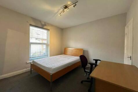 A neat double bedroom featuring a wooden bed fr...