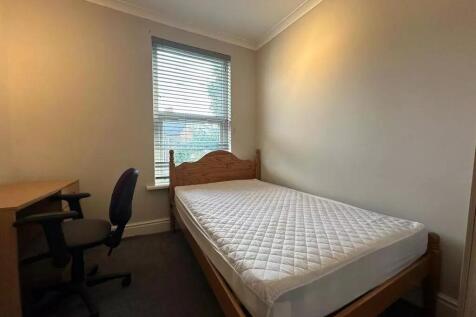 A cozy single bedroom featuring a wooden bed fr...