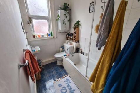 Bright, neatly arranged bathroom with a white s...