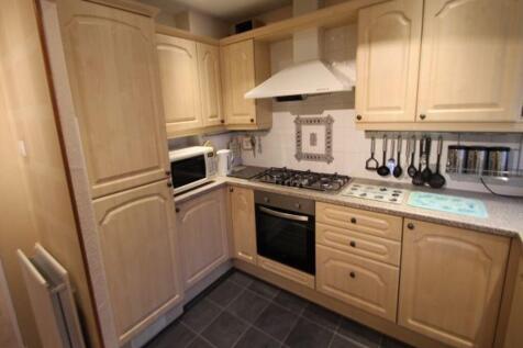 Warm, well-equipped kitchen with light wood cab...
