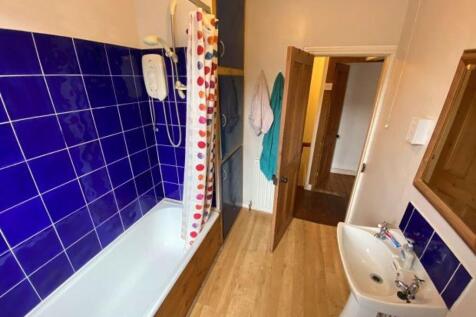Bright, clean bathroom with modern blue tiled s...