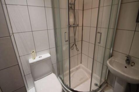Bright, tiled bathroom with a corner shower enc...