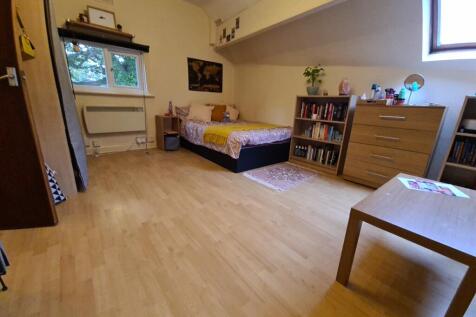 Neat, well-kept bedroom with light wood floors,...
