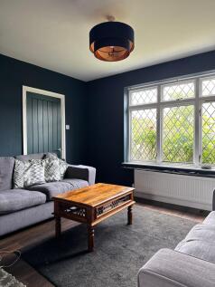 Bright, stylish living room with large leaded w...