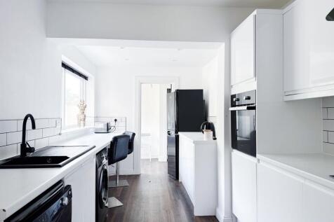 Bright, modern galley kitchen with white cabine...