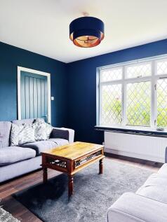 Bright, stylish living room with deep blue wall...
