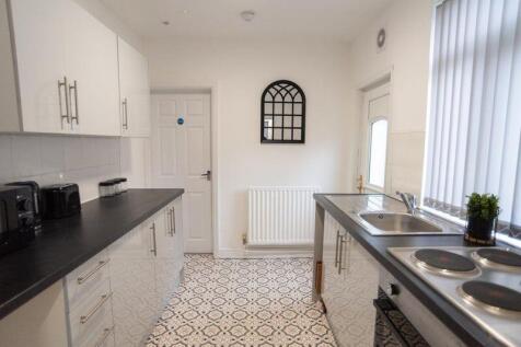 Bright, modern galley kitchen with white cabine...
