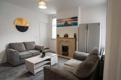 Bright, modern living room with matching grey s...