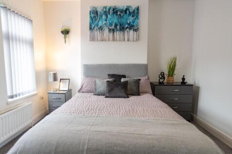 Bright, neatly styled bedroom with a soft grey ...