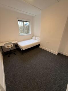 A cozy single bedroom featuring a comfortable b...