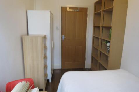 A tidy bedroom with a white bed and simple wood...