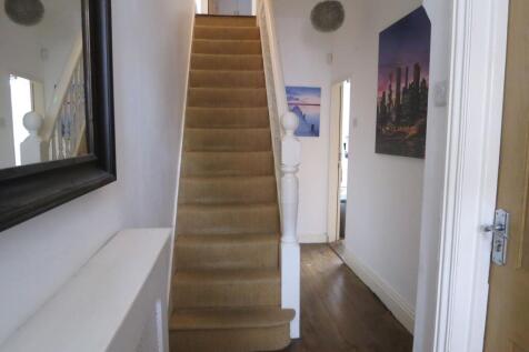 An indoor staircase with beige carpeted steps, ...