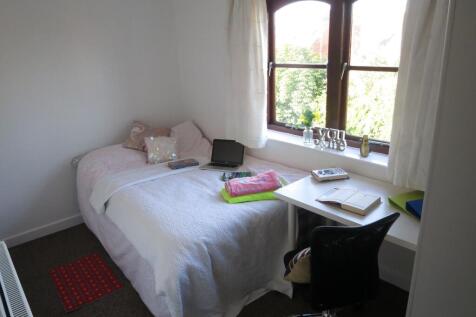 A cozy bedroom featuring a neatly made bed with...