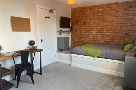 A modern, well-lit bedroom featuring a comforta...