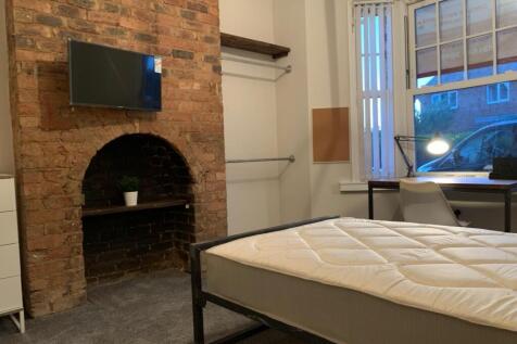 Spacious master bedroom with exposed brick feat...