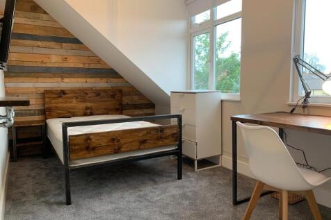 A modern bedroom featuring a wooden headboard a...