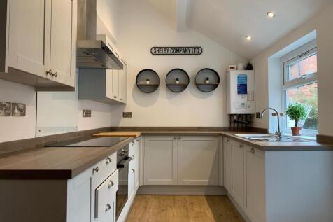 Bright, modern galley kitchen with white cabine...