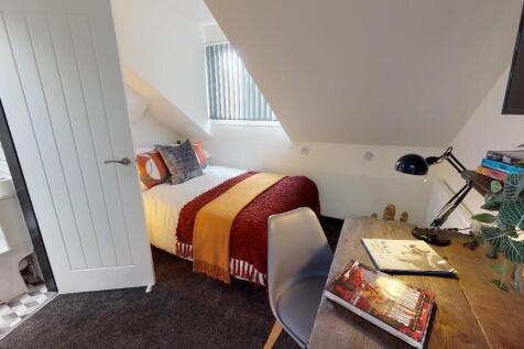 A cozy and well-lit bedroom with a comfortable ...