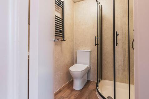 Modern bathroom featuring a toilet, enclosed sh...