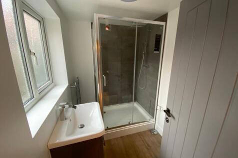 A neat and modern bathroom featuring a glass-en...