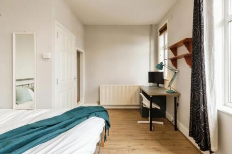 A bright and tidy bedroom featuring a large win...